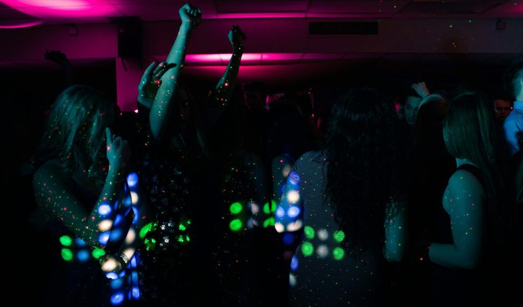 Group of people dancing under colorful lights inside a party bus, representing how a Budapest party bus experience works from start to finish.